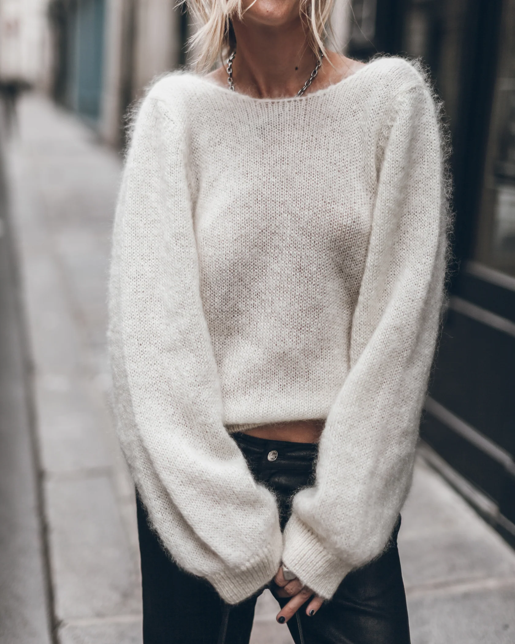 Pull dos-nu Mikuta en mohair écru noué dans le dos, porté avec un jean noir.