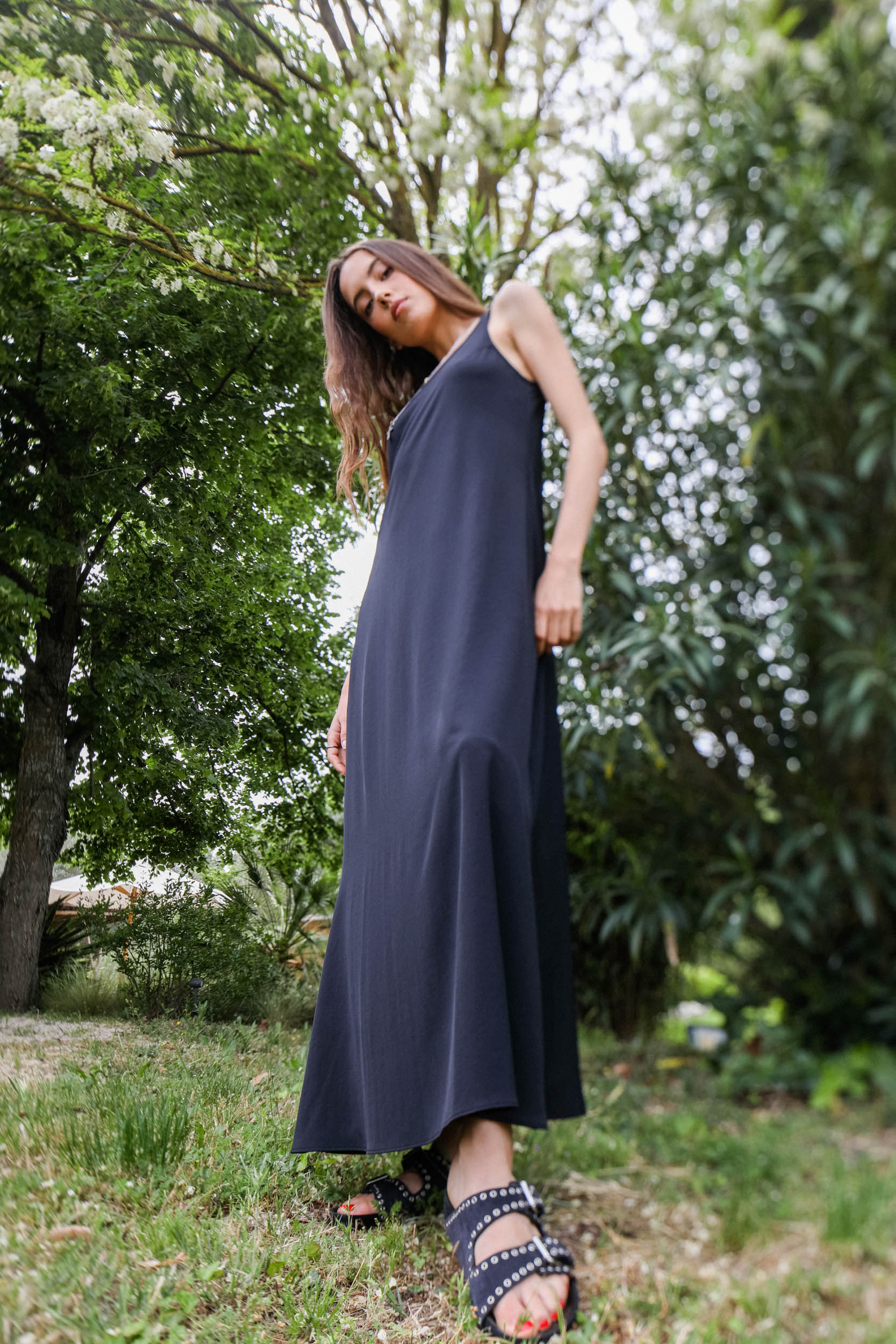 Robe longue noire forme débardeur fluide Vis à Vis. Porté avec des sandales cloutées. 