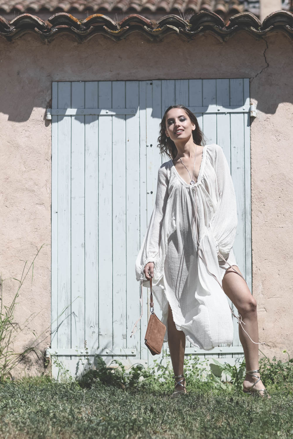 Robe manches longues en gaze de coton &eacute;cru Huiro Caravana. Port&eacute; avec une pochette en cuir naturel.