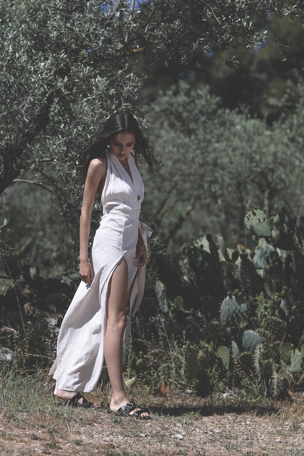 Robe longue fendue sur les jambes dos nu en coton &eacute;cru Tacoh Caravana. Port&eacute; avec des sandales en cuir noir Golden Goose. 