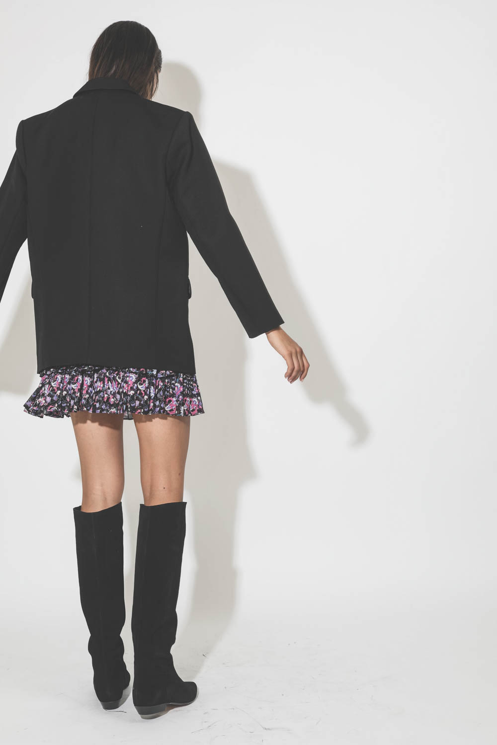 Mini jupe à volant imprimée fleurs noires et roses Naomi Marant Etoile. Porté avec des bottes en daim noir.