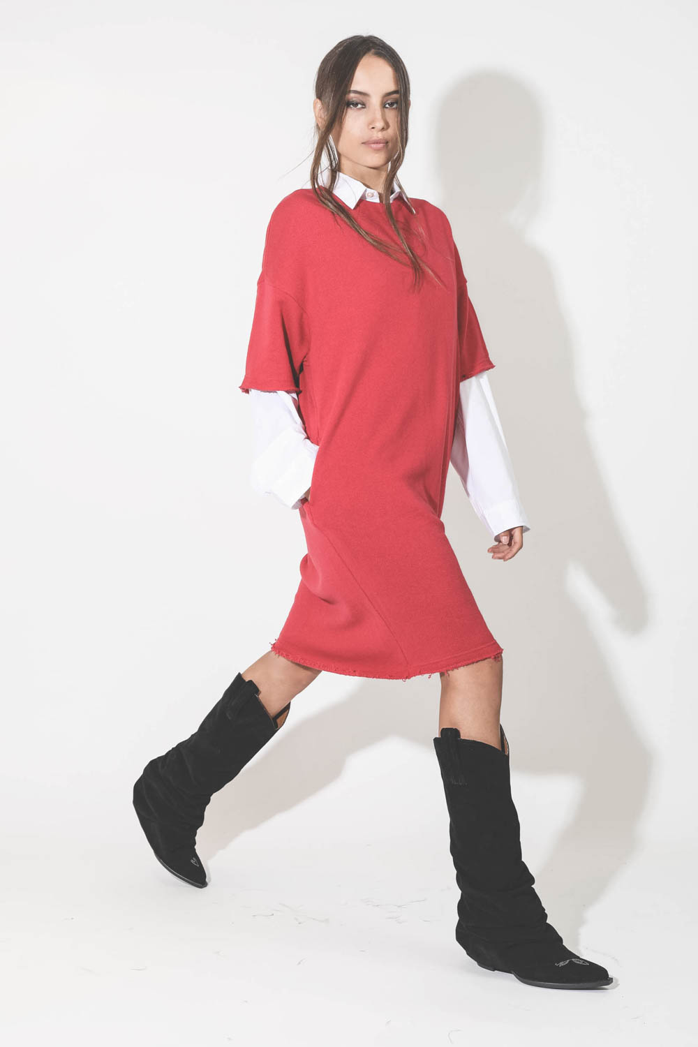 Robe midi manches courtes en sweat-shirt rouge R13. Porté avec des bottes santiags. Porté de profil.