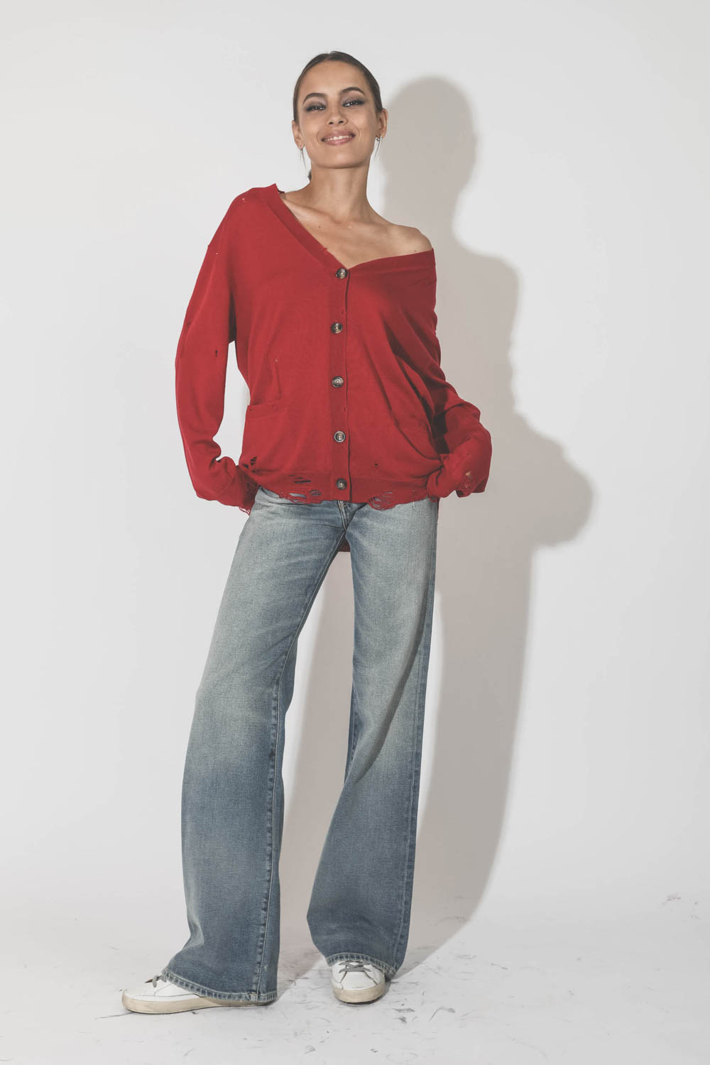 Gilet col V démaillé en 100% cachemire rouge R13. Porté avec un jeans évasé.