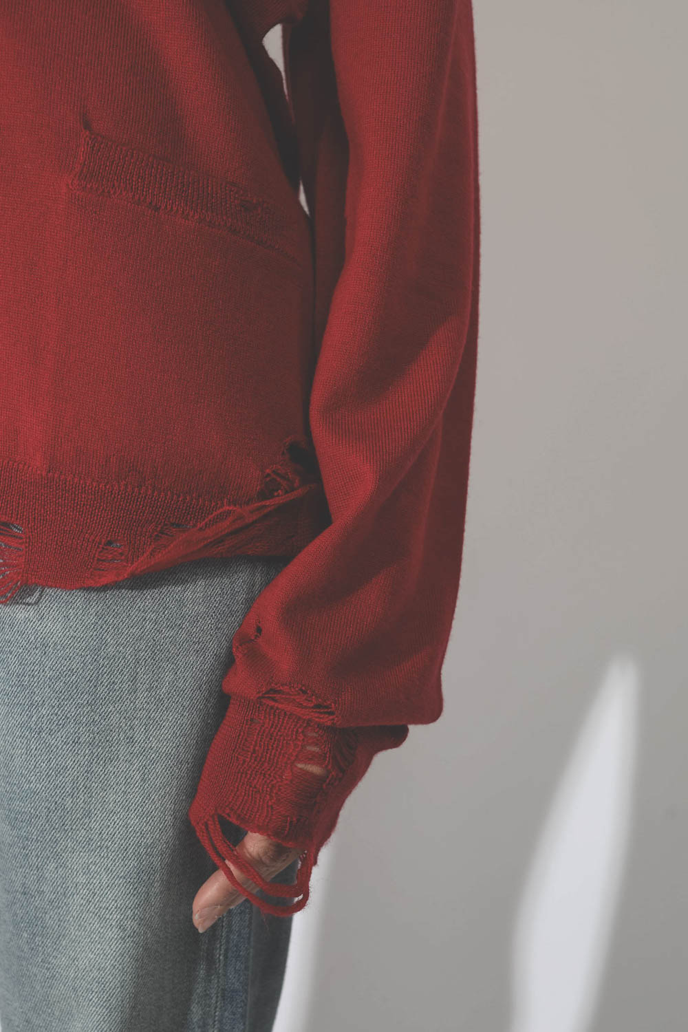 Gilet col V démaillé en 100% cachemire rouge R13. Détail bas de manche.