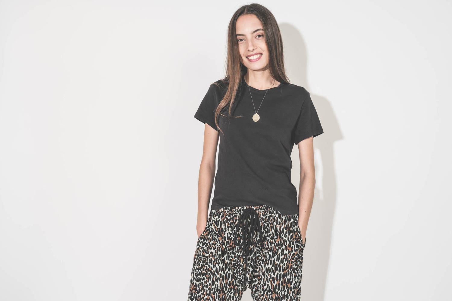 Collier chaine avec pendentif Rio N°2 Pascale Monvoisin en or jaune et diamants. Porté sur un tee-shirt noir manches courtes Boxy Crew et un pantalon sarouel imprimé léopard The Great. 