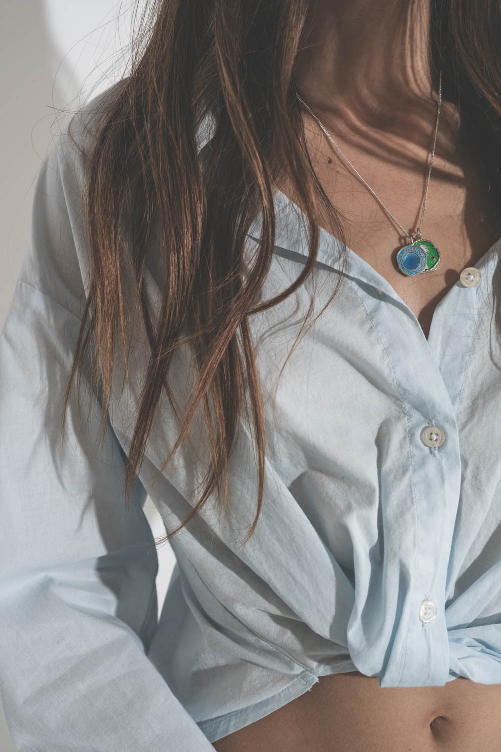 Pendentif en argent émail bleu Hydra Pascale Monvoisin. Porté en accumulation avec une médaille en émail verte Faro et une chemise bleu ciel R13.