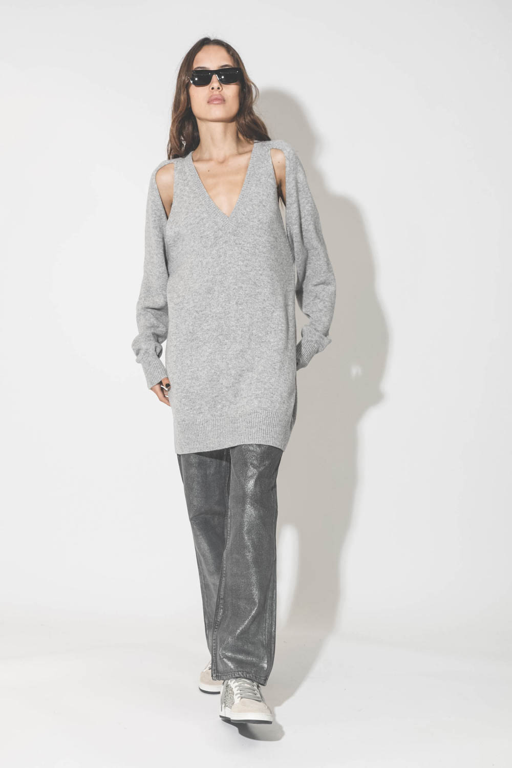 Robe pull en cachemire gris col V emmanchures ouvertes. Porté avec un jeans gris enduit.
