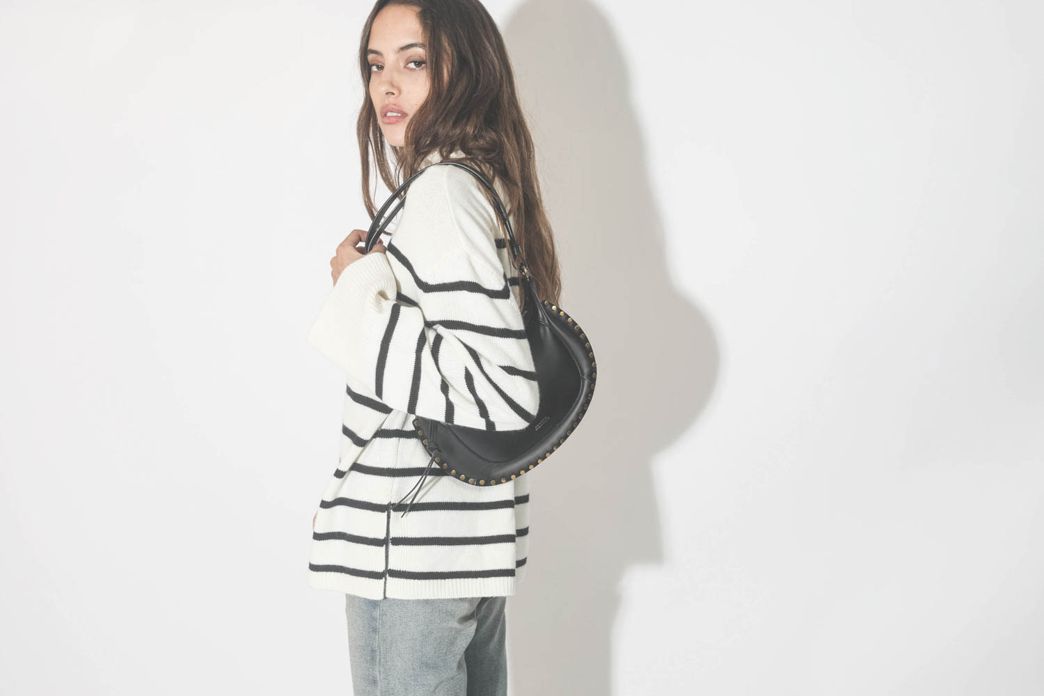 Pull marin col montant à rayure ivoire et noir Courtney Anine Bing. Porté avec un sac en cuir noir clouté.
