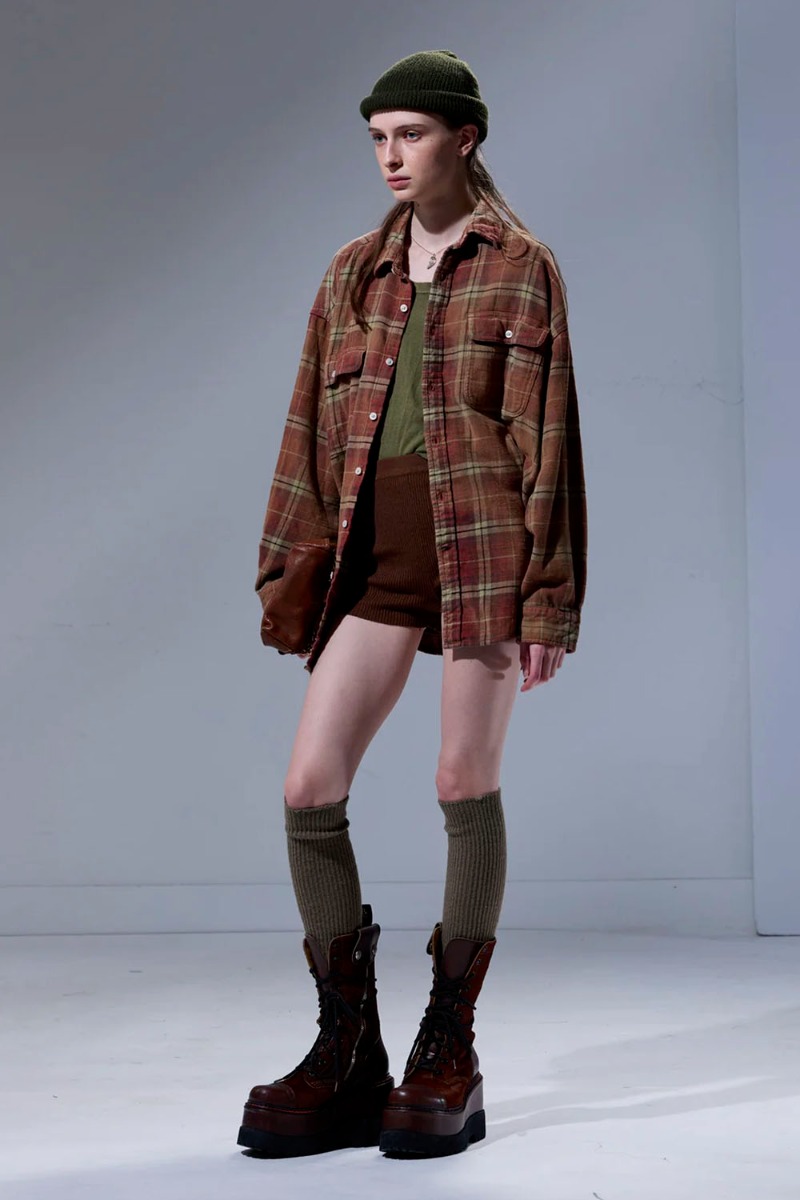 Chemise oversize Boyfriend Shirt R13 en flanelle à carreaux rouges et marron, portée ouverte sur un tee-shirt. 