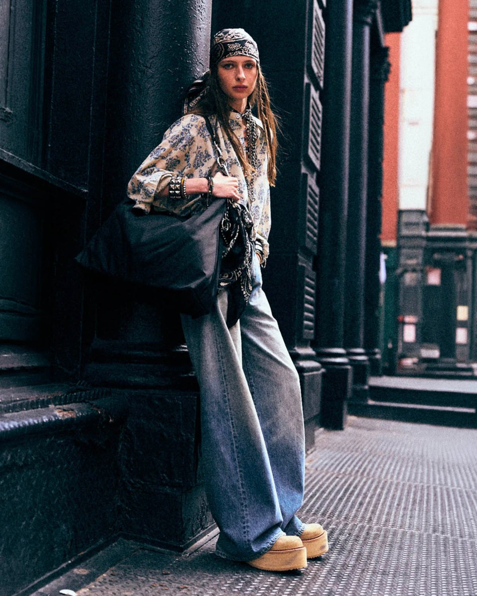 Chemise Pleat Front R13 en coton &eacute;cru imprim&eacute; floral bleu ciel, port&eacute;e de profil avec un jean bleu clair.