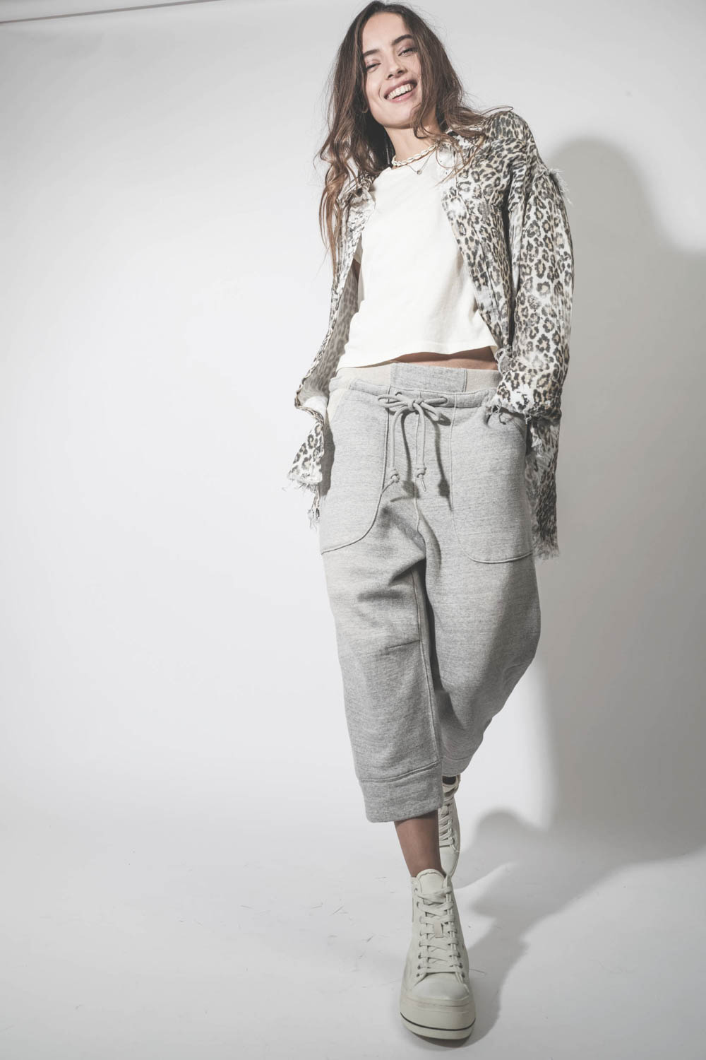 Produit Pantalon de jogging court et oversize en molleton gris chiné Deconstructed Cropped Sweatpant Heather Grey R13. Porté avec des sneakers compensées en toile blanche.
