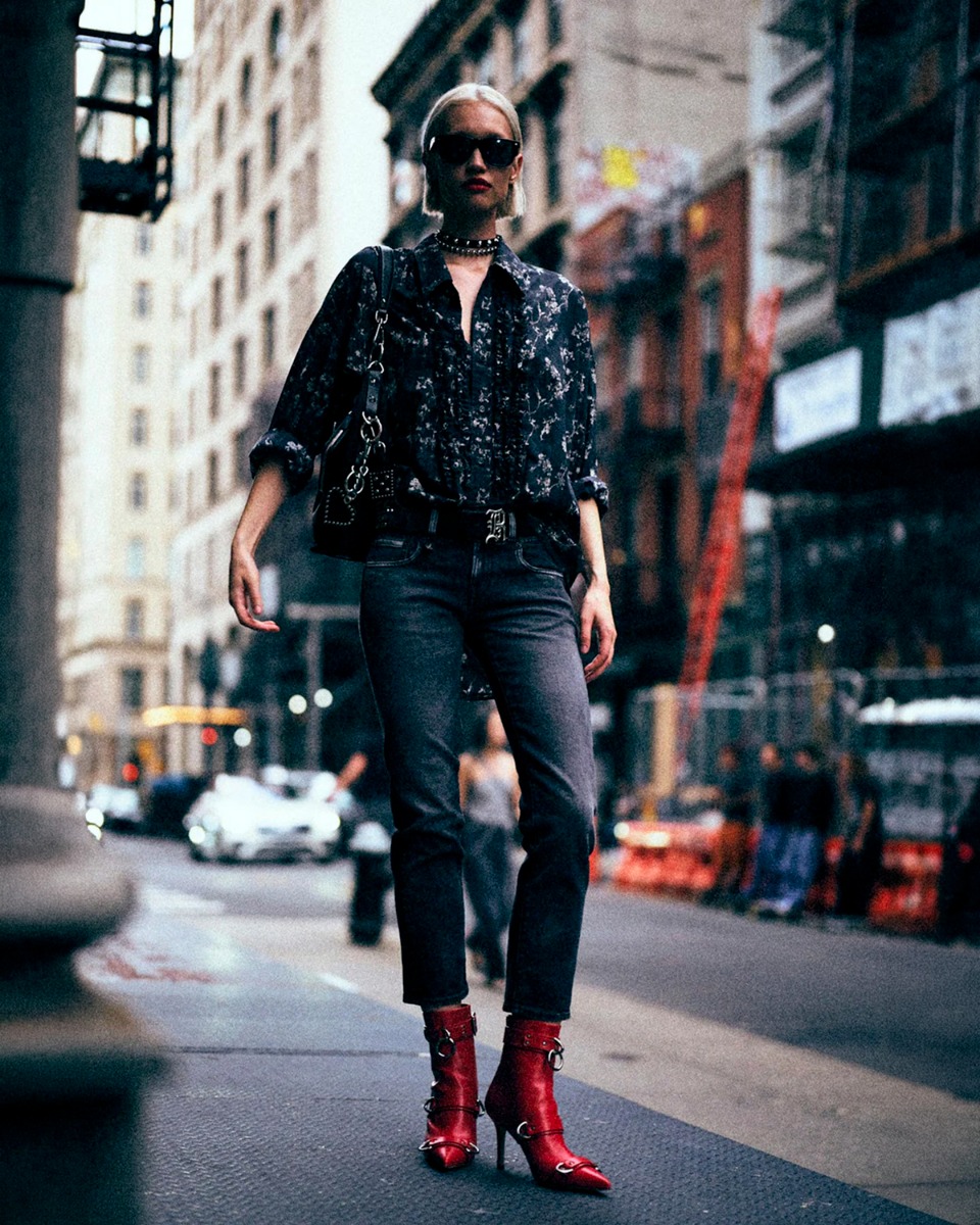 Jean slim raccourcie Boy Straight R13 en denim noir d&eacute;lav&eacute; Essex Black Stretch, port&eacute; de face avec une chemise &agrave; jabots imprim&eacute; floral noire.