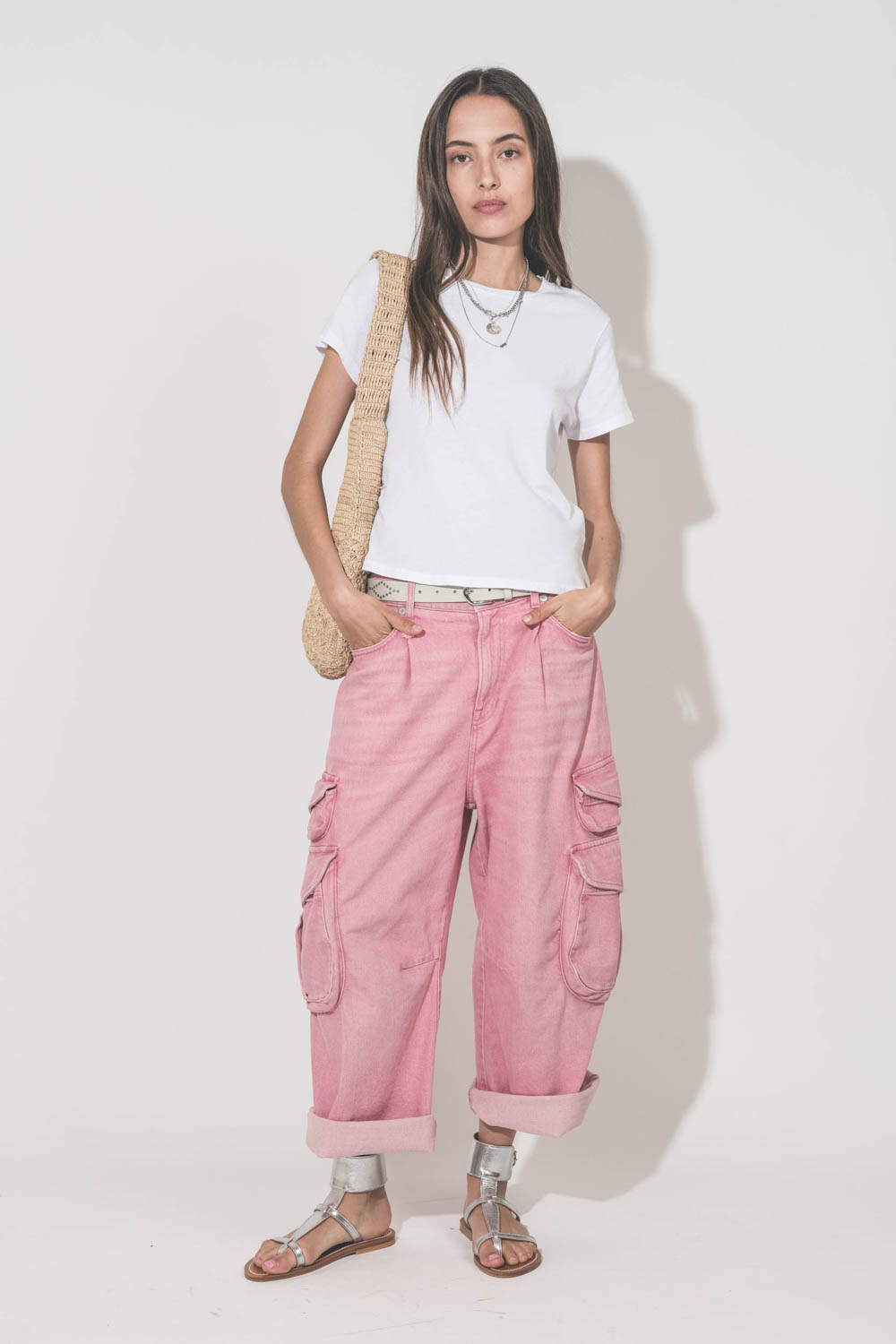 Jean taille basse oversized en toile rose multi-poches Cargo R13 denim. Porté avec un tee-shirt blanc Little The Great, une ceinture en cuir blanc Liliana Isabel Marant, des sandales en cuir argent Caravelle K.Jacques St-Tropez, un sac en raphia naturel P