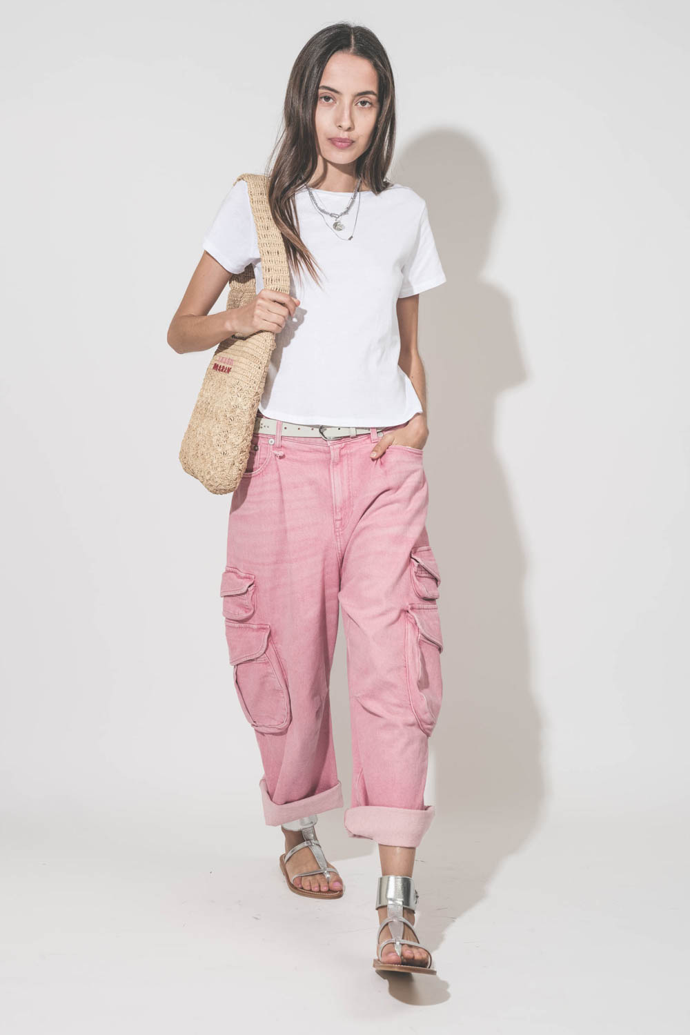 Jean taille basse oversized en toile rose multi-poches Cargo R13 denim. Porté avec un tee-shirt blanc Little The Great, une ceinture en cuir blanc Liliana Isabel Marant, des sandales en cuir argent Caravelle K.Jacques St-Tropez, un sac en raphia naturel P
