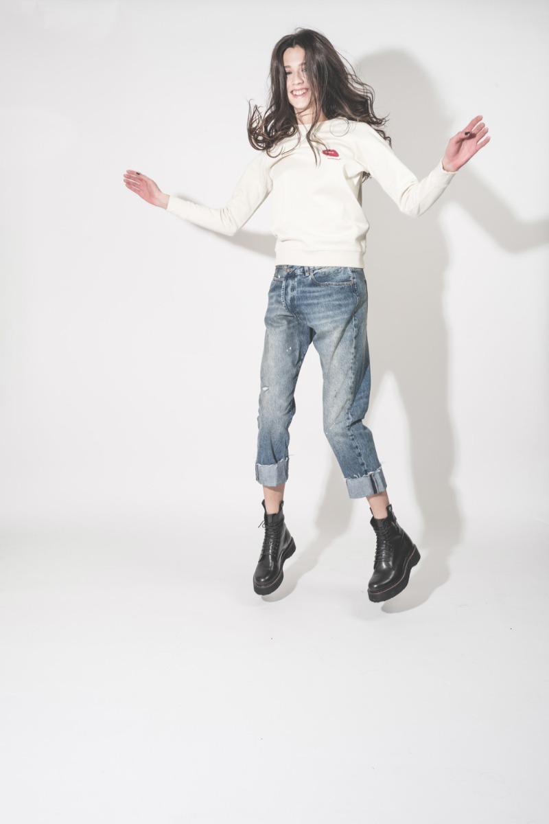 Jean Crossover R13 en denim bleu d&eacute;lav&eacute; Jasper, port&eacute; avec un sweatshirt Bisous.