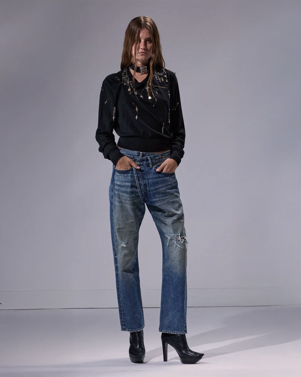 Jean crossover R13 en denim bleu déchiré Léo Blue, porté de face avec un pull noir R13.