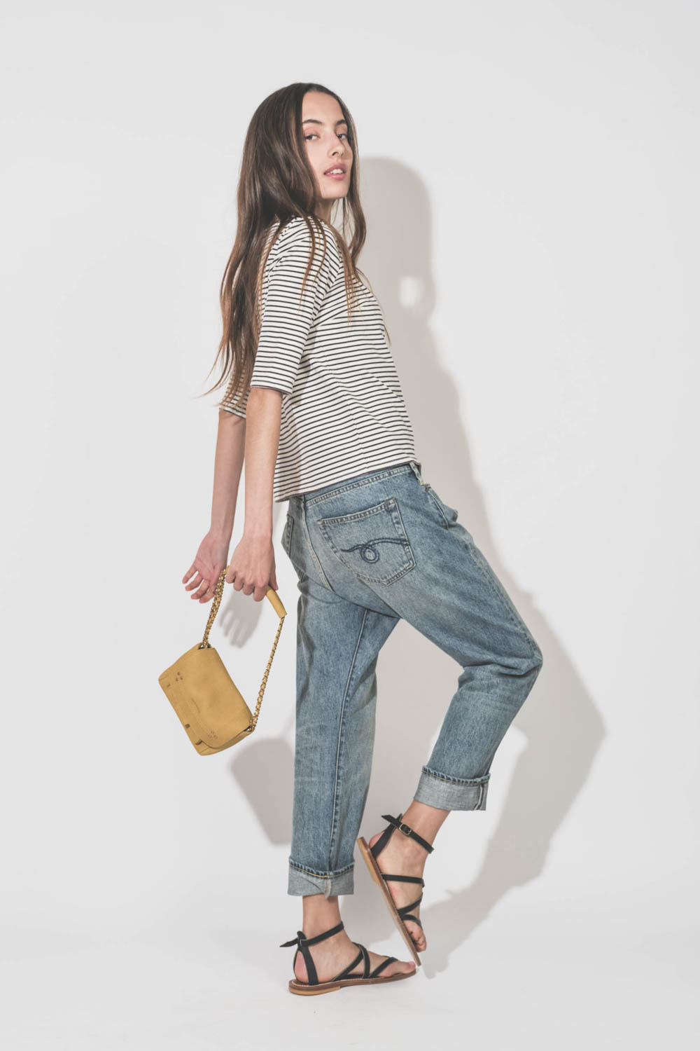 Jean Crossover Lena Blue R13. Porté de profil avec une marinière R13 et un sac Lulu S jaune Jérôme Dreyfuss.