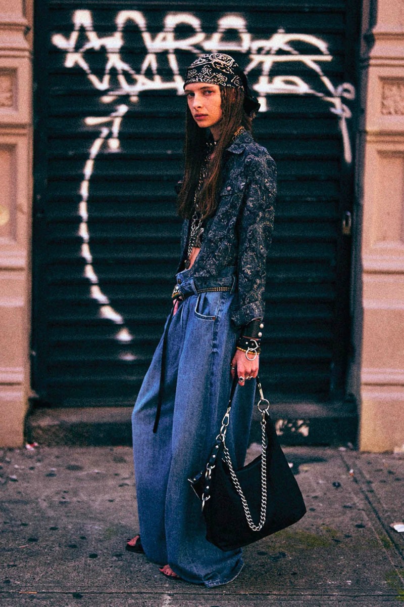 Jean Pleated Waistband R13 en denim bleu d&eacute;lavage &laquo; Concrete Blue &raquo;, port&eacute; de profil avec une ceinture.