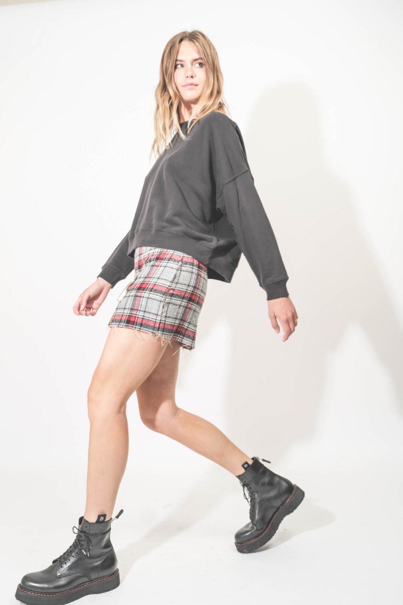 Mini-jupe réversible Raw Cut R13. Portée de profil avec des rangers en cuir noir.