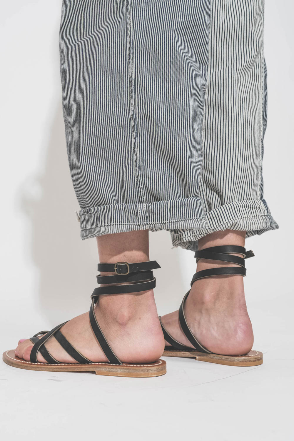 Pantalon oversize à rayures bleues Cargo Railroad R13. Détail de l'ourlet avec un petit revers. Porté avec des sandales en cuir noir Zenobie K.Jacques Saint-Tropez. 