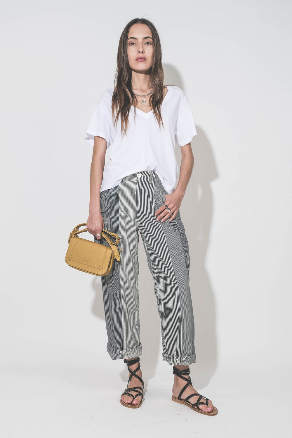 Pantalon oversize à rayures bleues Cargo Railroad R13. Porté avec un tee-shirt blanc col V The Great, des sandales plates en cuir noir Zenobie K.Jacques Saint-Tropez et un sac Pepito S jaune Mimosa Jérôme Dreyfuss. Bijoux en argent Maria Black, Pascale Mo