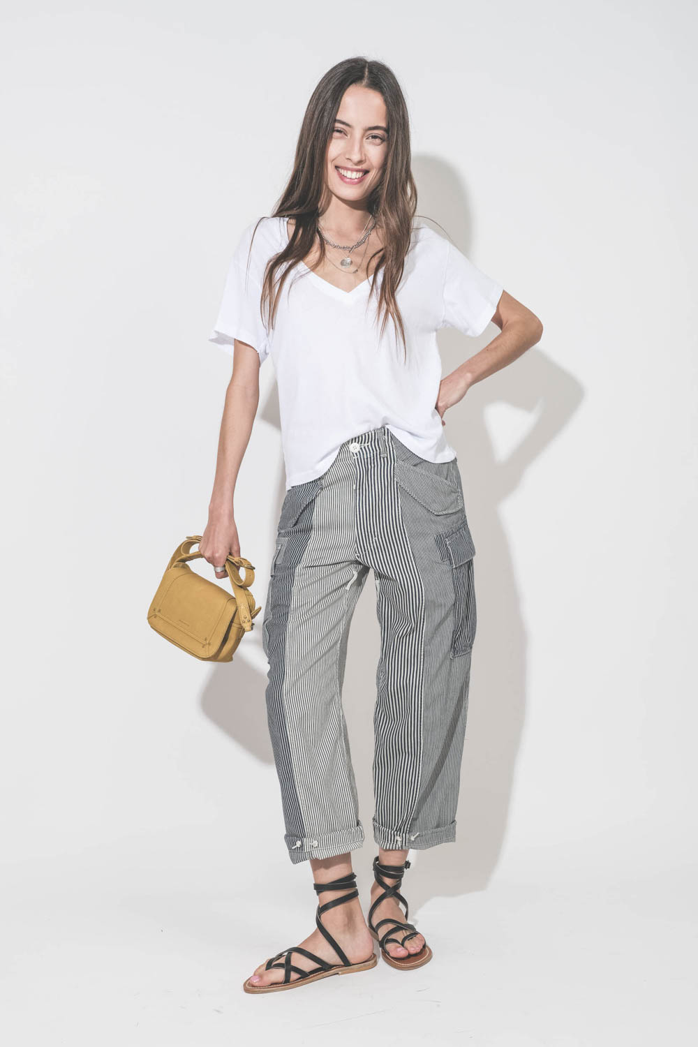 Pantalon oversize à rayures bleues Cargo Railroad R13. Porté de face avec un tee-shirt blanc col V The Great, des sandales plates en cuir noir Zenobie K.Jacques Saint-Tropez et un sac Pepito S jaune Mimosa Jérôme Dreyfuss. Bijoux en argent Maria Black, Pa