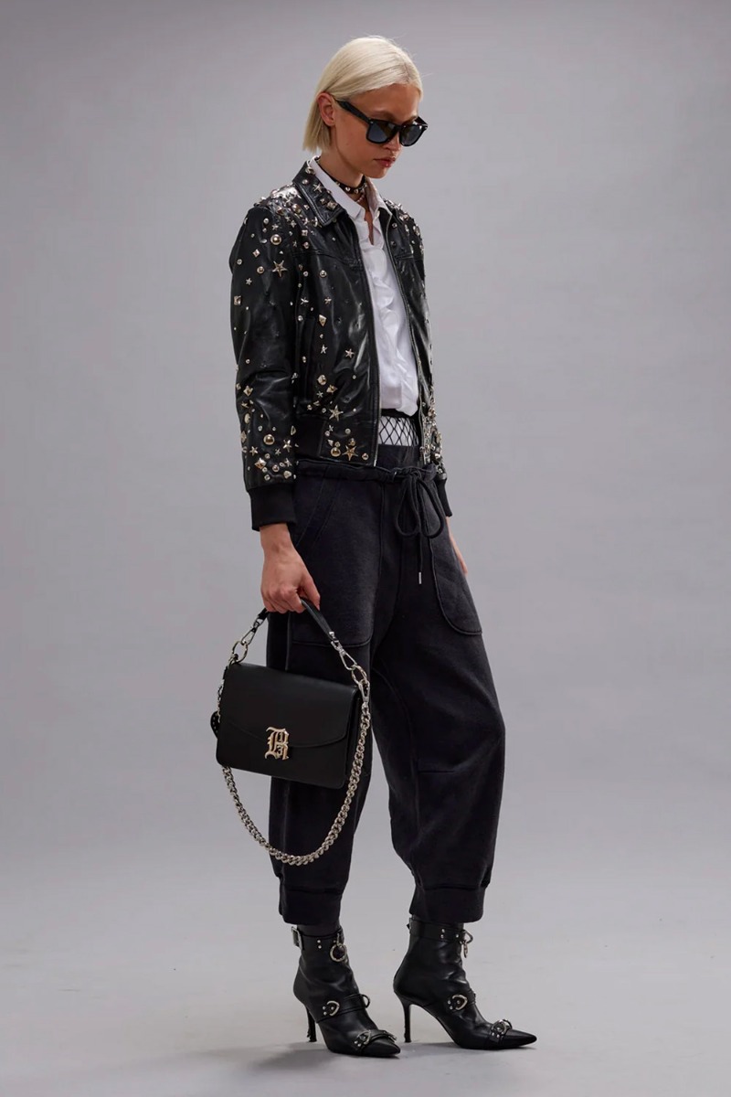 Pantalon de jogging court Deconstructed Cropped Sweatpant R13 en coton japonais noir, port&eacute; de profil avec des boots &agrave; talons R13.