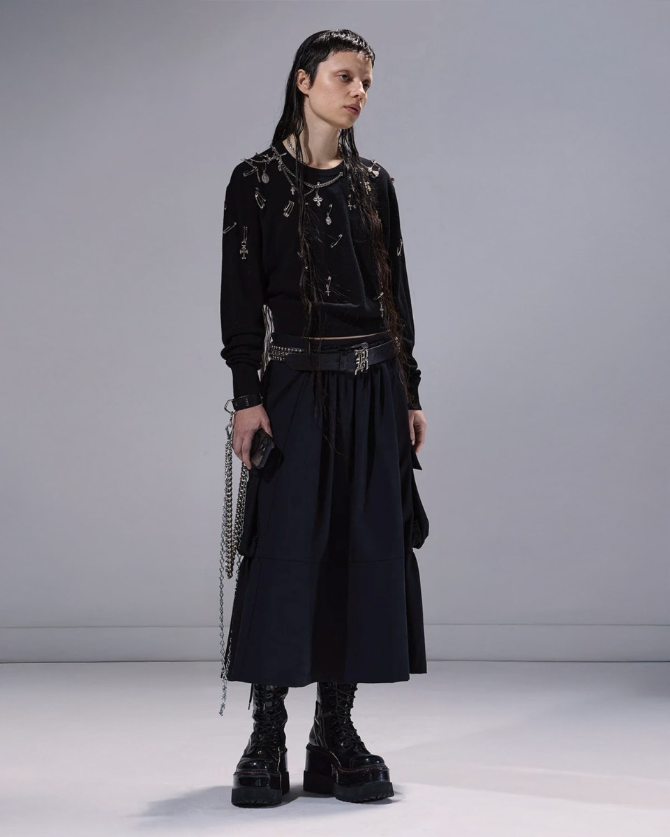 Pull Tight Waist Crewneck Sweater R13 en laine noire, orné de bijoux argentés, porté de face avec une ceinture logo R13. 