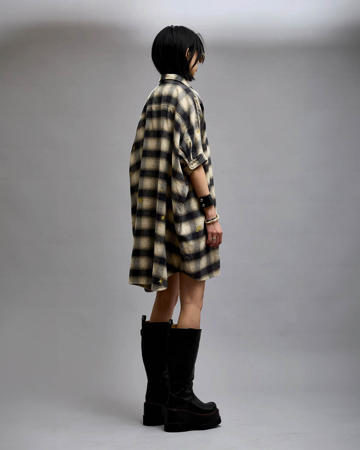 Robe chemise manches courtes oversize à carreaux taches de peinture dorées Oversized Relaxed Shirtdress R13. Porté de profil dos.