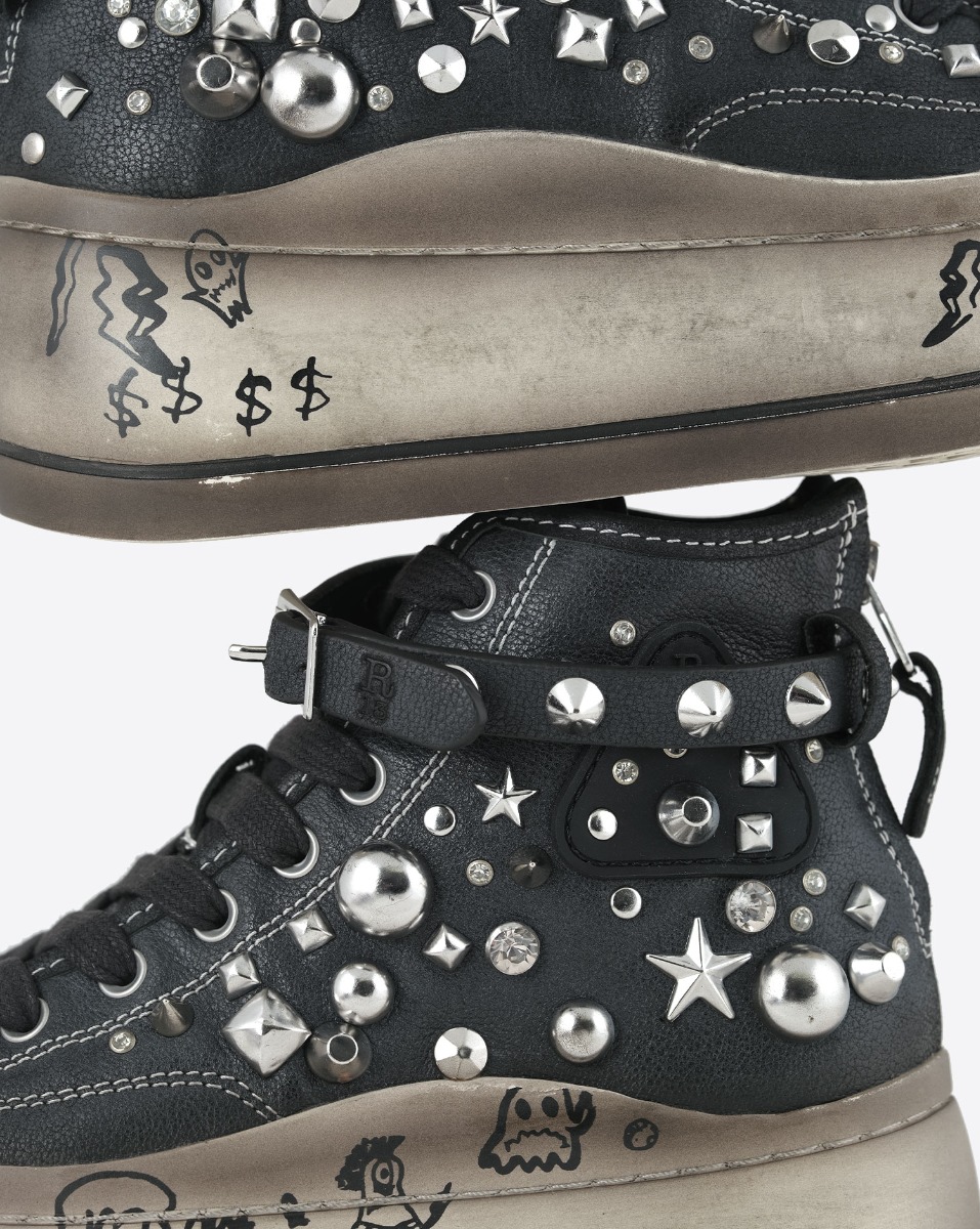 Baskets compens&eacute;es Kurt R13 en toile noire clout&eacute;e en m&eacute;tal argent&eacute; et bracelet de cheville en cuir noir. Semelle &eacute;cru avec graffitis. D&eacute;tail de la mati&egrave;re. 