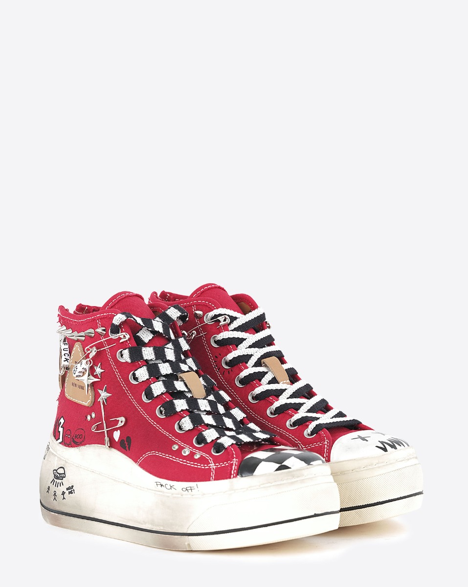 Baskets compens&eacute;es Kurt R13 en toile rouge customis&eacute;es avec des clous et des &eacute;pingles &agrave; nourrice. D&eacute;tails des lacets et bout de la basket noir et blanc. Vue de face.