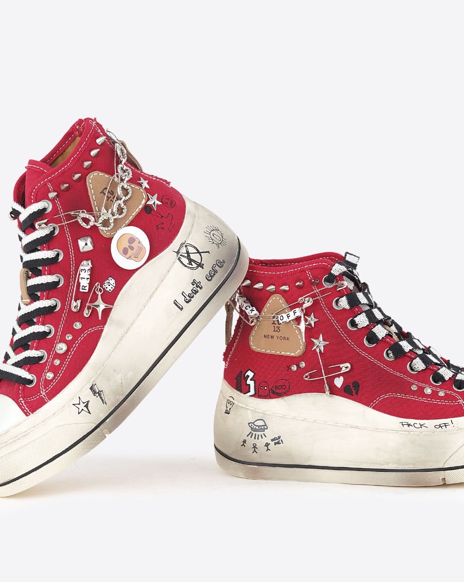 Baskets compens&eacute;es Kurt R13 en toile rouge customis&eacute;es avec des clous et des &eacute;pingles &agrave; nourrice. D&eacute;tails des semelles avec des graffitis noirs. 