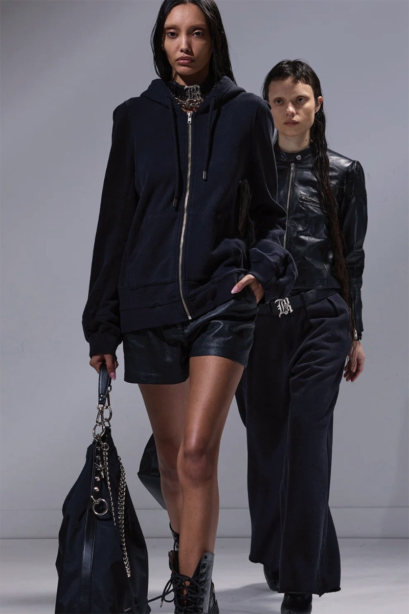 Produit Veste à capuche zippée Elongated Hoodie R13 en molleton noir, portée fermée avec un short en cuir noir.