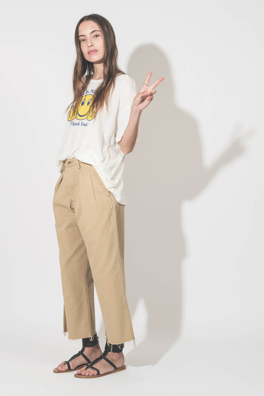 Tee-shirt manches courtes en coton et cachemire écru imprimé devant Smiley doigts d'honneur "Have A Nice Day. Thank You !" R13. Porté avec un pantalon large chino beige Denimist et des sandales plates en cuir noir Caravelle K.Jacques St-Tropez.