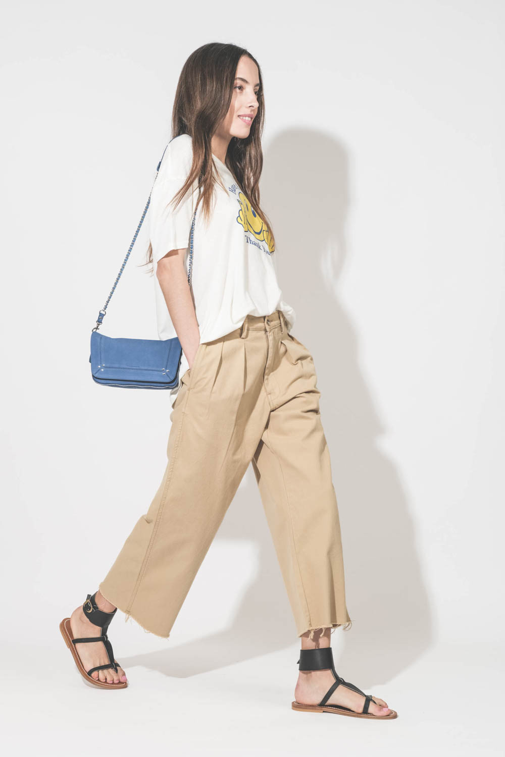 Tee-shirt manches courtes en coton et cachemire écru imprimé devant Smiley doigts d'honneur "Have A Nice Day. Thank You !" R13. Porté de profil avec un pantalon large chino beige Denimist et des sandales plates en cuir noir Caravelle K.Jacques St-Tropez. 