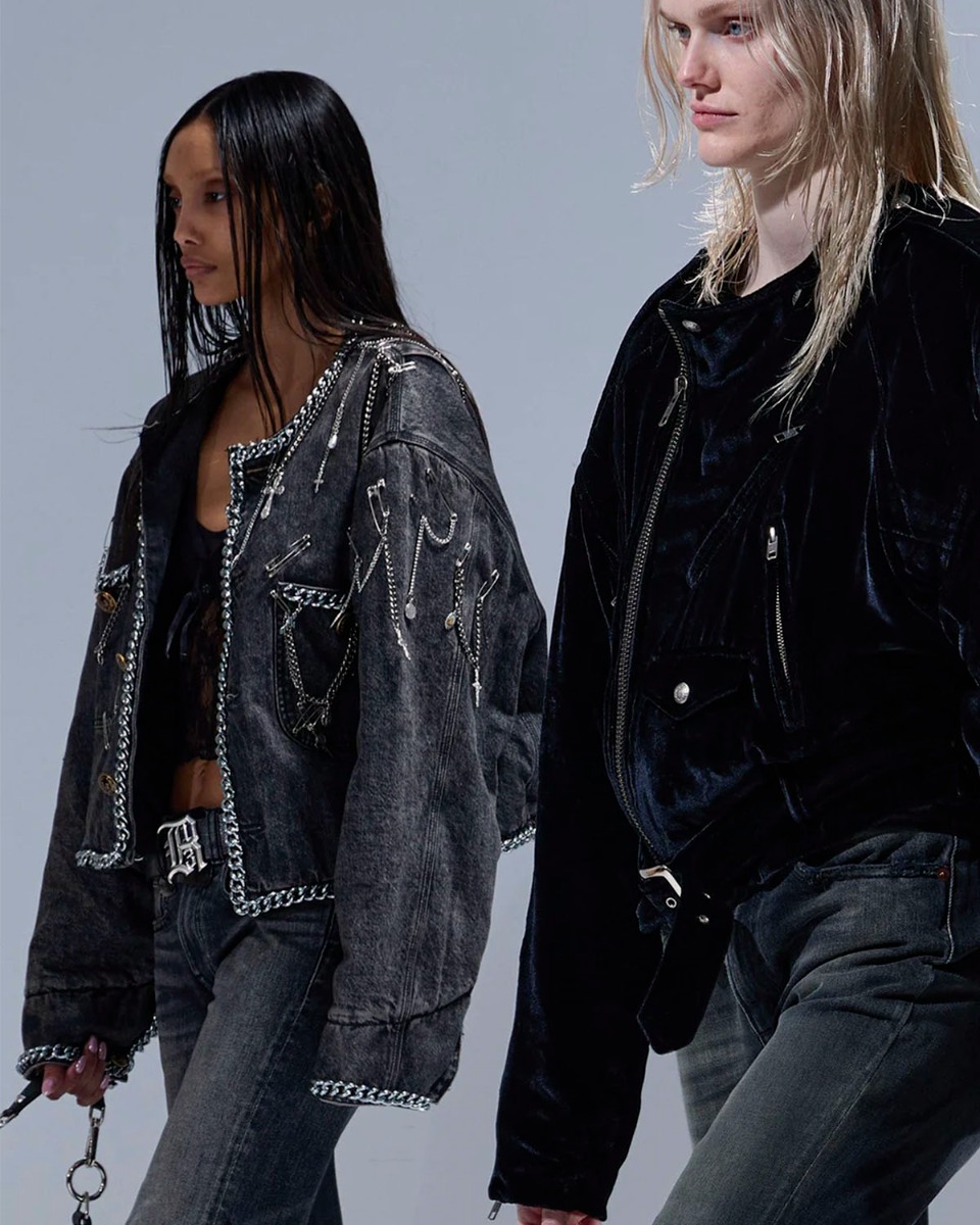 Veste courte Chain Embellished Cropped Chore Jacket R13 en denim gris foncé, customisée avec des chaînes, des épingles à nourrice et des médailles en métal argenté. Portée de profil.