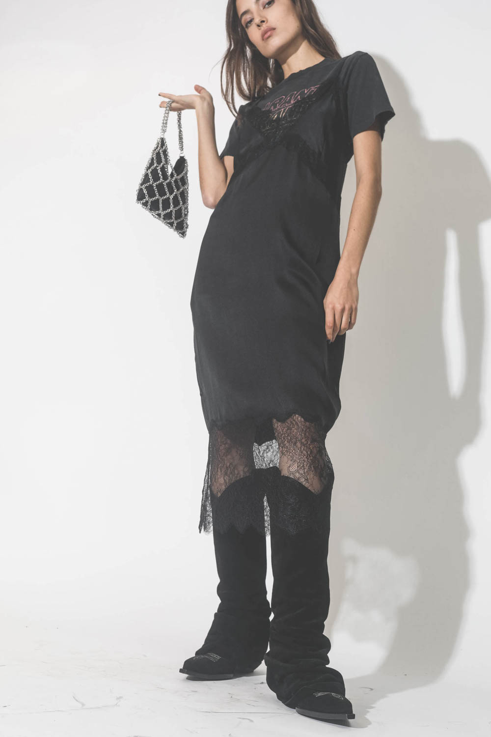 Robe fines bretelles en soie et dentelle noire Amélie Anine Bing. Porté avec des bottes santiags noires.