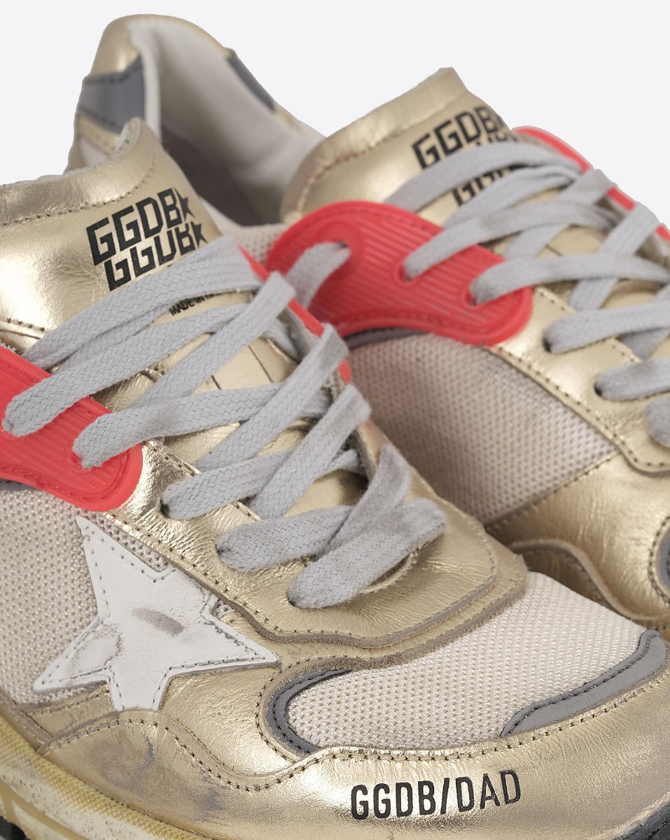 Sneakers Running Dad Golden Goose femme dorée étoile blanche. Détail du passage rouge pour les lacets gris.