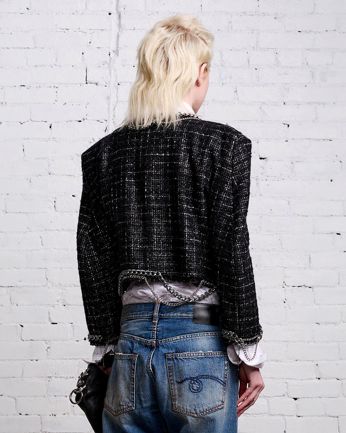 Veste courte épaulée en tweed avec des chaines et rubans esprit "Chanel Punk" R13. Porté de dos.