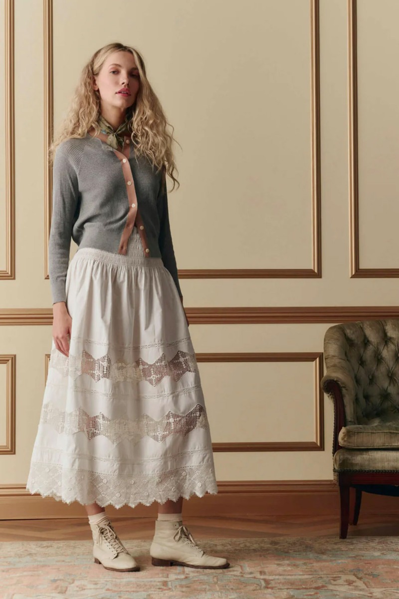 Jupe longue Rosette Crochet The Great en coton et dentelle blanche, port&eacute;e de face avec un gilet.