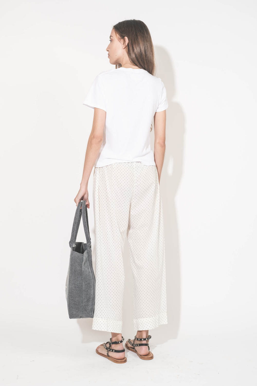 Pantalon Sarouel en voile de coton blanc à pois Easy Sleep The Great. Porté de dos avec un tee-shirt manches courtes blanc Little The Great et des sandales en cuir noir clouté Deltapyr K.Jacques St Tropez. Cabas en toile anthracite logo Marant Yenky petit