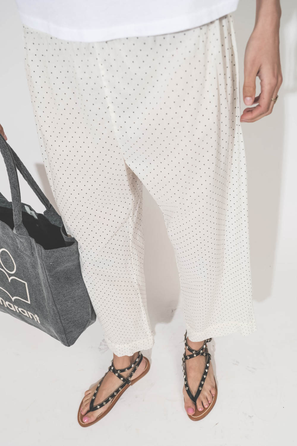 Pantalon Sarouel en voile de coton blanc à pois Easy Sleep The Great. Porté avec un tee-shirt manches courtes blanc Little The Great et des sandales en cuir noir clouté Deltapyr K.Jacques St Tropez. Cabas en toile anthracite logo Marant Yenky petit Isabel