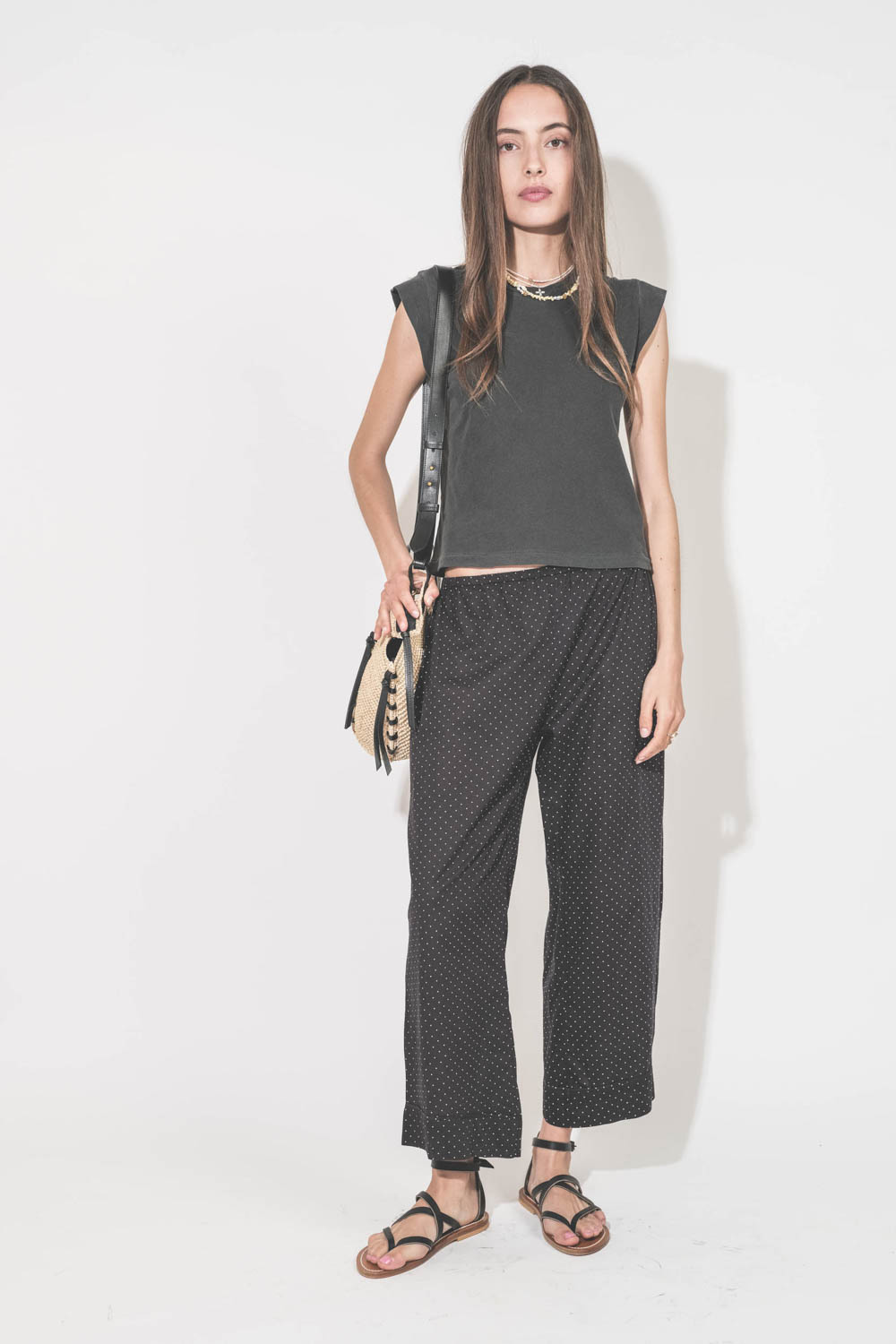 Pantalon taille basse en voile de coton noir à pois blancs Easy Sleep The Great. Porté avec un tee-shirt sans manches noir Peak Shoulder The Great et des sandales en cuir noires Zenobie K.Jacques St-Tropez. Panier en osier bandoulière en cuir noire Tampa 