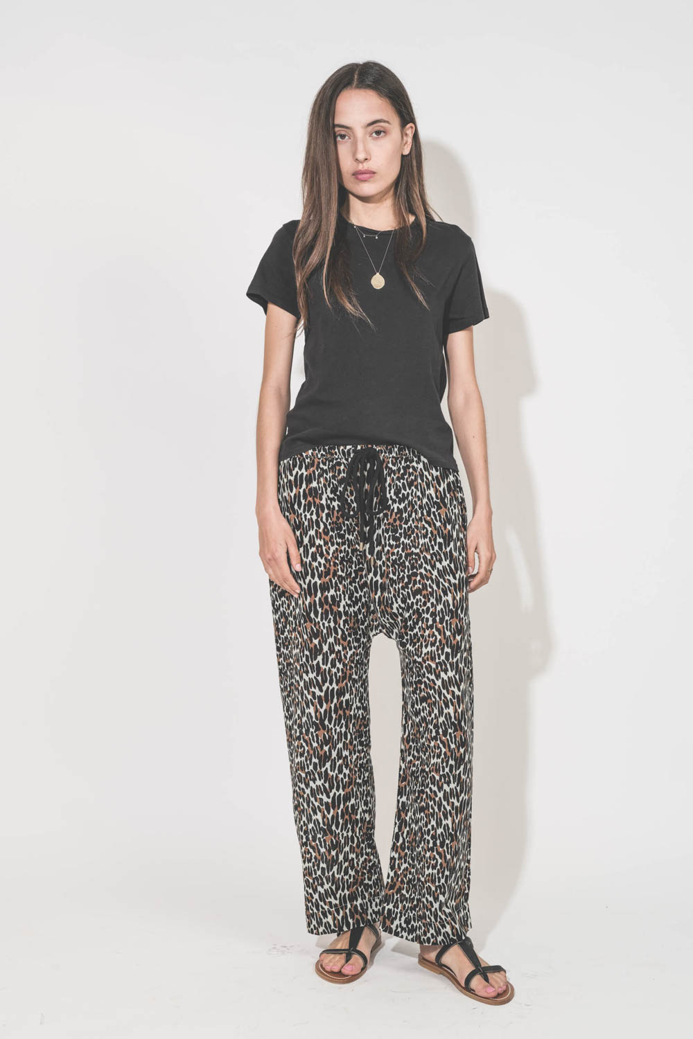 Pantalon Sarouel en voile de coton imprimé léopard Reef The Great. Porté avec une tee-shirt manches courtes noir Boxy Crew The Great et des sandales en cuir noir Artimon K.Jacques St-Tropez. Collier en or jaune et diamants Rio et collier en or jaune et sa