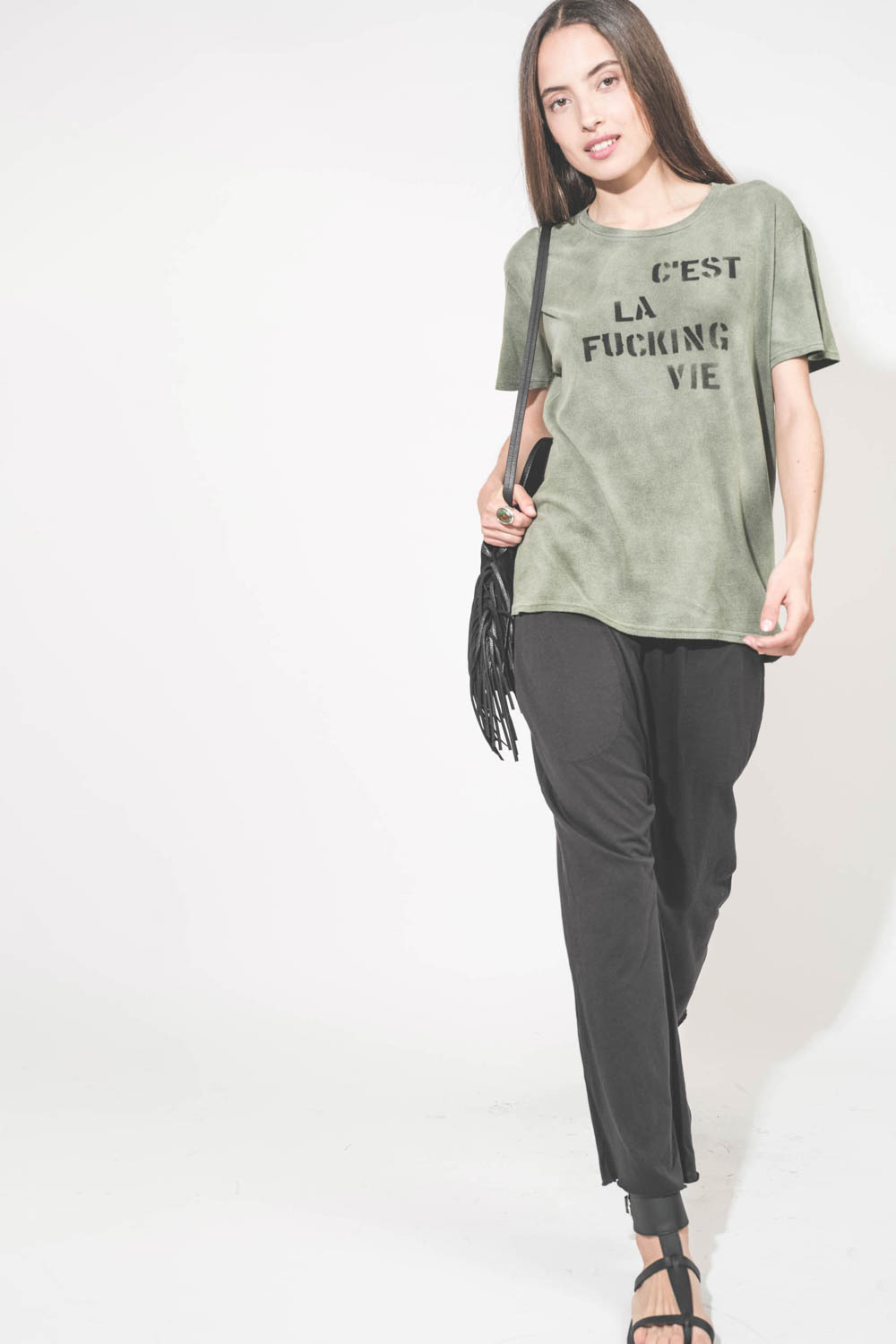 Pantalon sarouel court en jersey noir The Great. Porté avec un tee-shirt manches courtes à message "C'est la Fucking Vie" R13 et des sandales en cuir noir Ebene semelles noires Caravelle K.Jacques St-Tropez. Mini-sac en cuir suédé à franges noir Paco S Jé