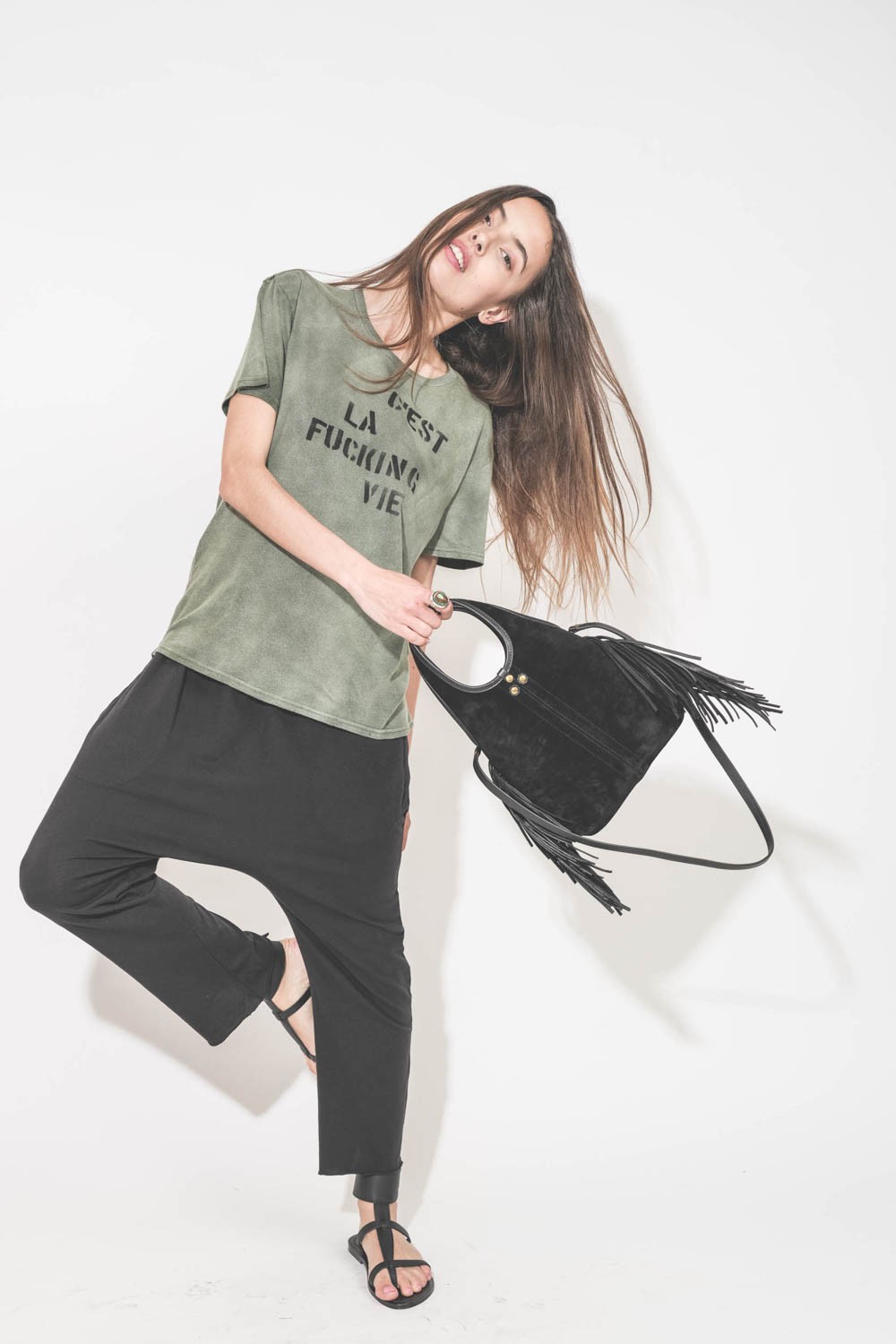 Pantalon sarouel court en jersey noir The Great. Porté avec un tee-shirt manches courtes à message "C'est la Fucking Vie" R13 et des sandales en cuir noir Ebene semelles noires Caravelle K.Jacques St-Tropez. Mini-sac bandoulière en cuir suédé à franges no