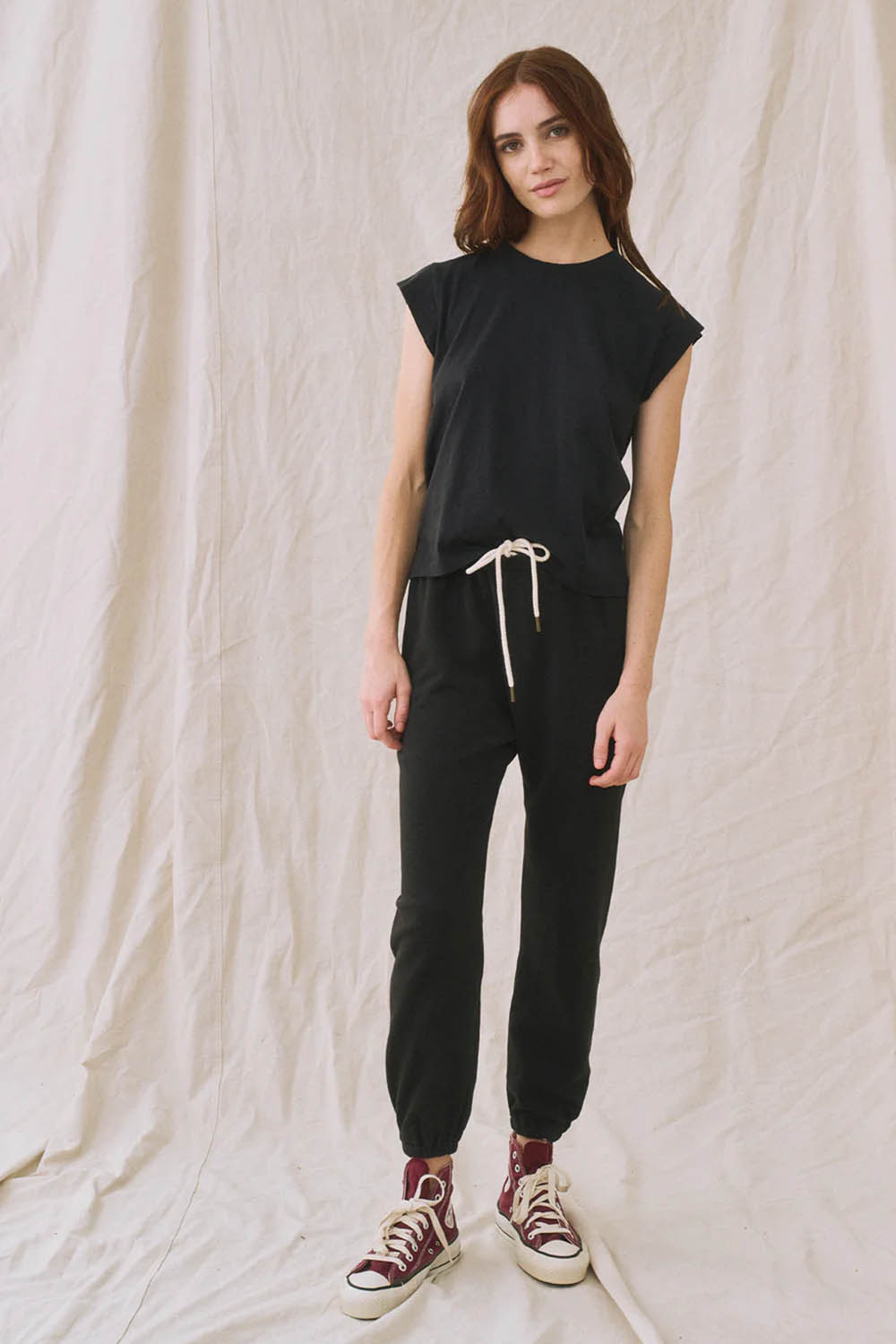 Produit Tee-Shirt Peak Shoulder The Great en coton noir. Porté avec un jogging noir vu de face. 