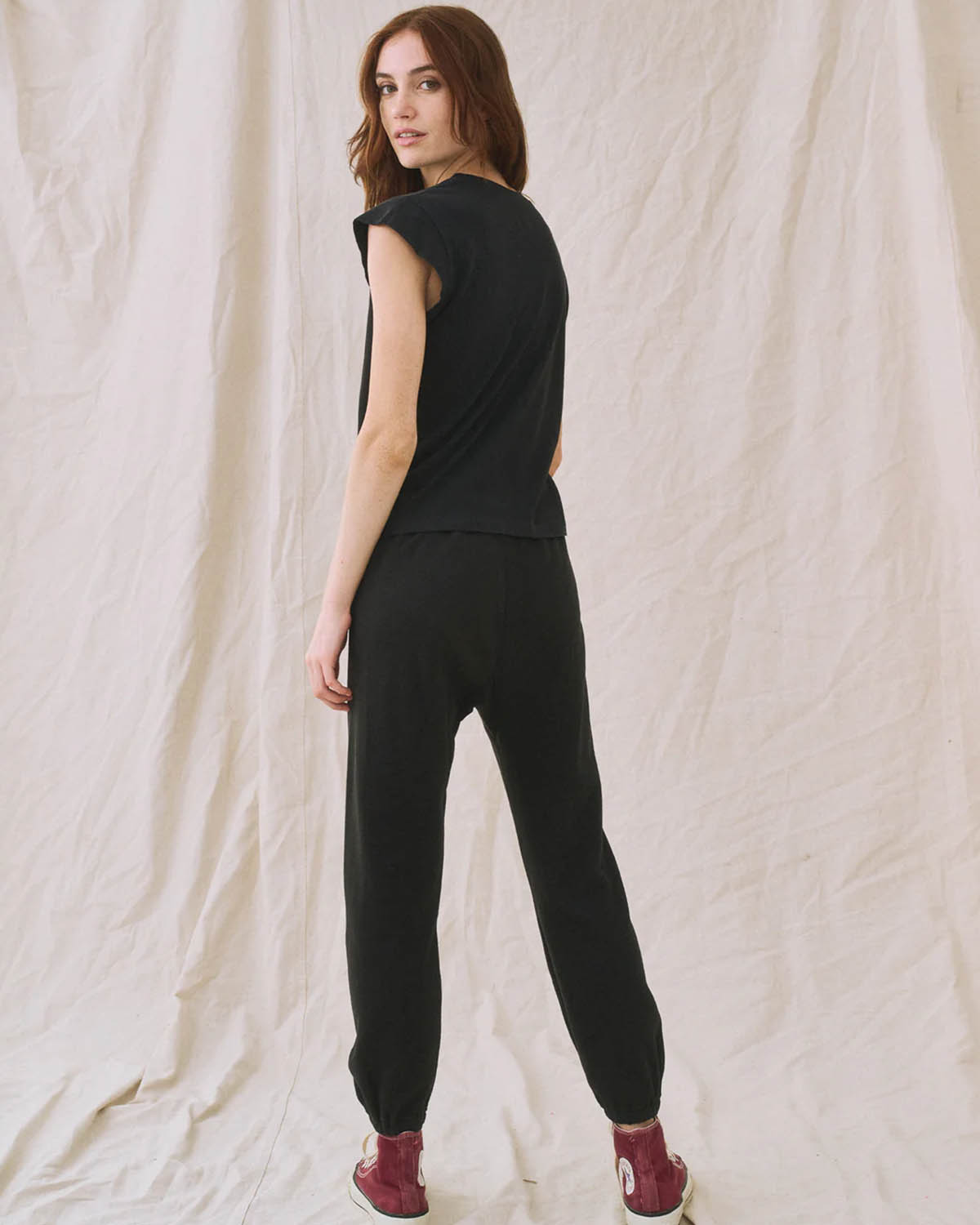 Tee-Shirt Peak Shoulder The Great en coton noir. Porté avec un jogging noir vu de dos. 