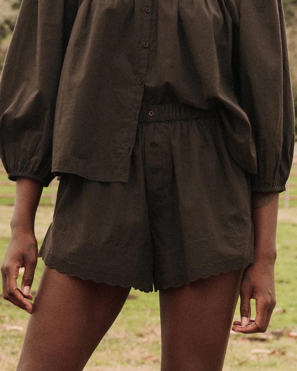 Short court en coton brodé taille élastique avec bouton Eyelet Noir. Thème Sleep. Porté de face avec une blouse coordonnée. Détail de la fermeture boutons. 