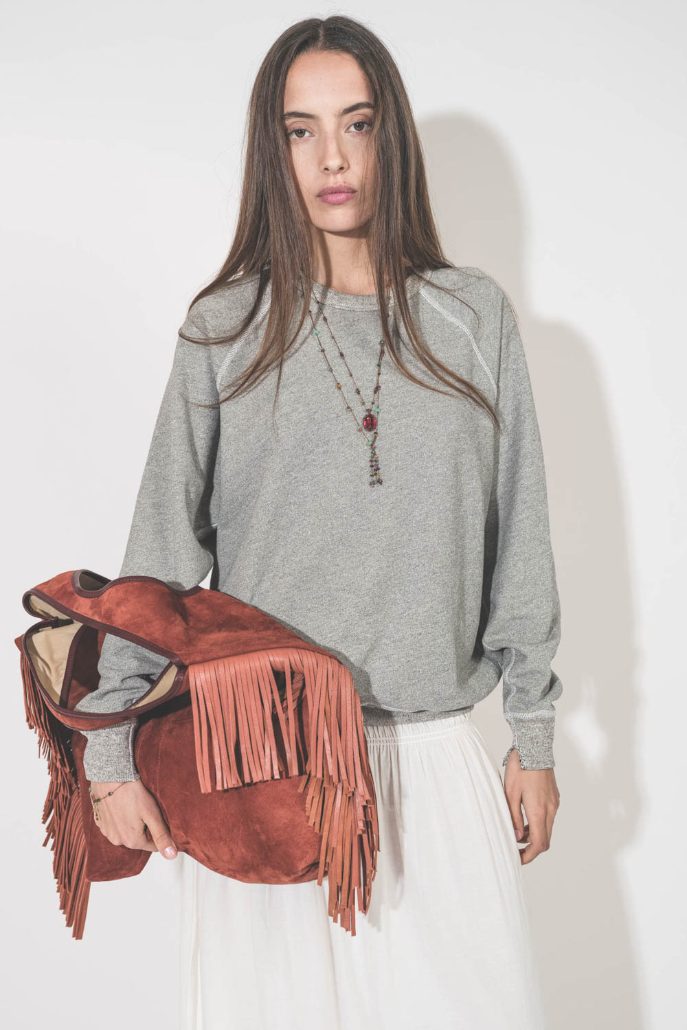 Sweat-shirt classique manches longues col rond col rond surpiqures contrastées blanches College The Great. Porté avec une jupe longue en coton blanc The Great et un cabas à franges Paco Terracotta Jérôme Dreyfuss. Sautoirs et bracelet Tibétain Sharing.